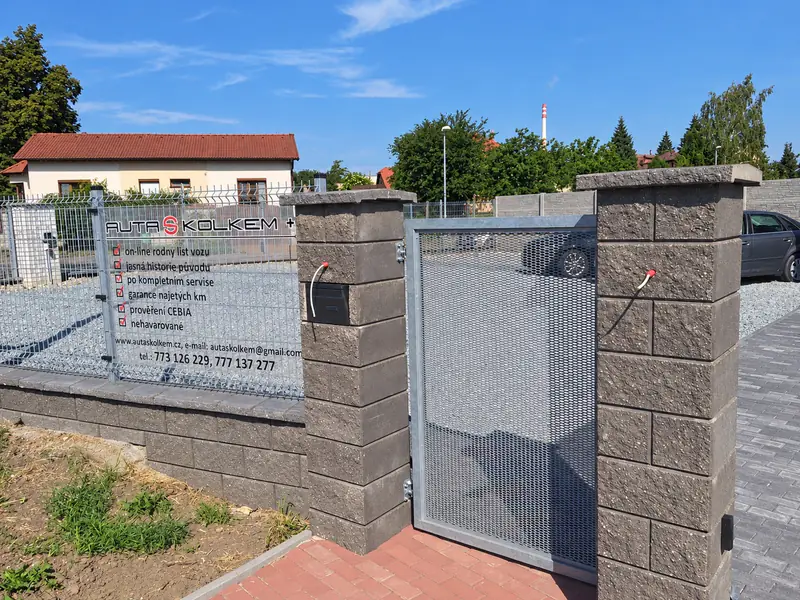 Vstupní branka mezi sloupky z betonových tvárnic a plotová podezdívka