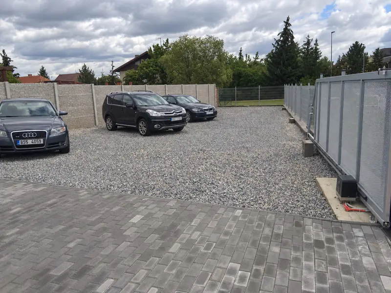 Hotová příjezdová cesta z betonové dlažby a štěrkové parkoviště u firmy
