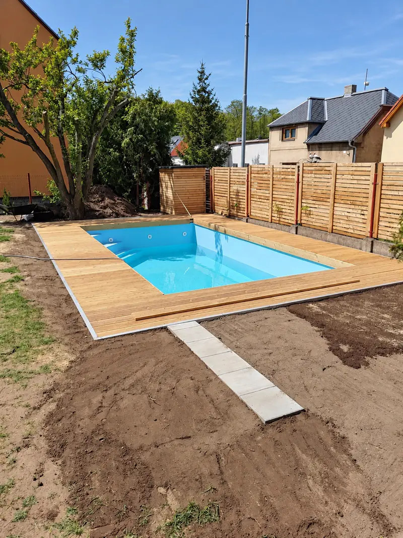 Hotový zapuštěný bazén s dřevěnou terasou na zahradě