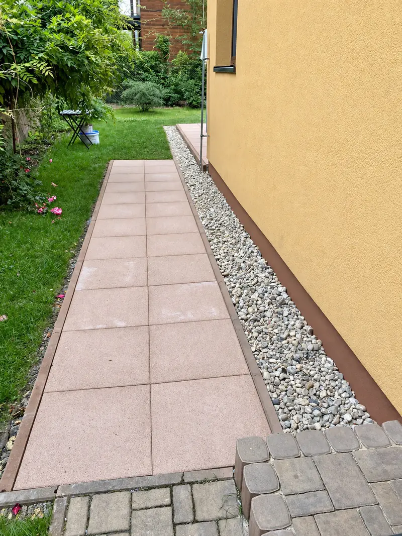 Chodník z velkoformátové dlažby podél domu se štěrkovým okapovým chodníkem