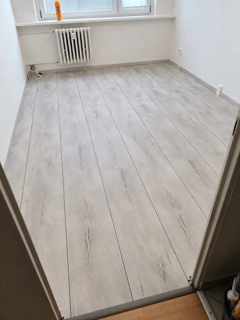 Nová světlá plovoucí podlaha v prázdné místnosti